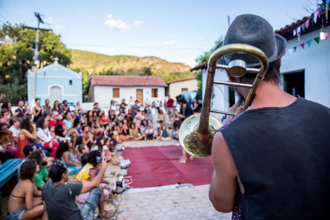Músico de trombone de costas para a plateia que lota a praça